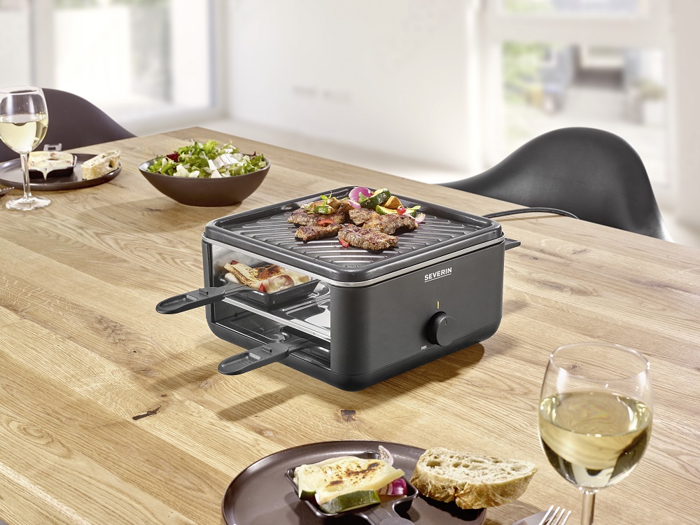 Grill raclette Severin RG2360 600 W pod skosem na stole w trakcie przygotowywania dania